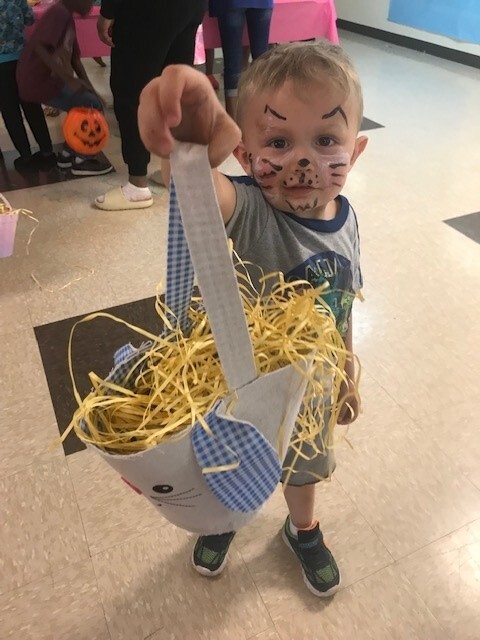 One boy holding up a basket with Easter grass and eggs.