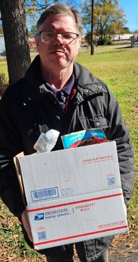 A man outside holding a box from the Christmas food giveaway.