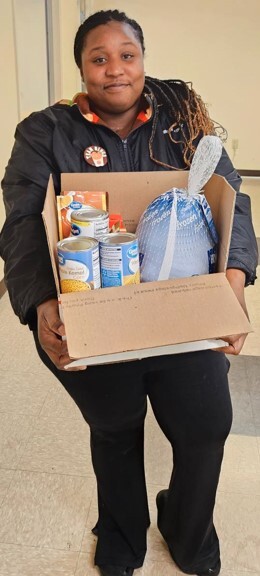 A woman holding a box from the Christmas food giveaway.