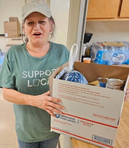 A woman standing next to a box from the Christmas food giveaway.